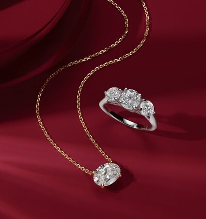 An oval solitaire pendant and a three stone diamond ring