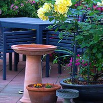 A brick patio with a bird feeder and some planters.