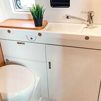 Camper bathroom featuring sink vanity and toliet.