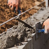 A contractor leveling freshly poured concrete on a wall.