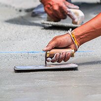A trowel being used to level poured concrete.