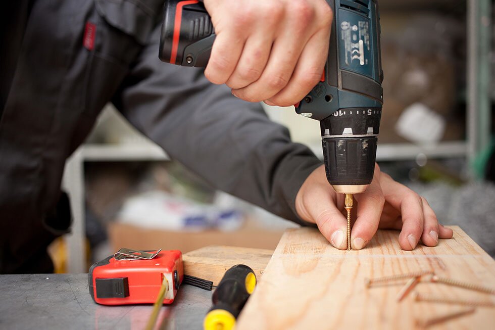 A DIY'er using a drill to attach lumber.