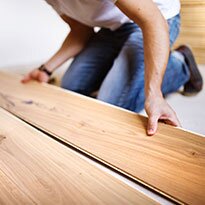 A person installing new hardware flooring.