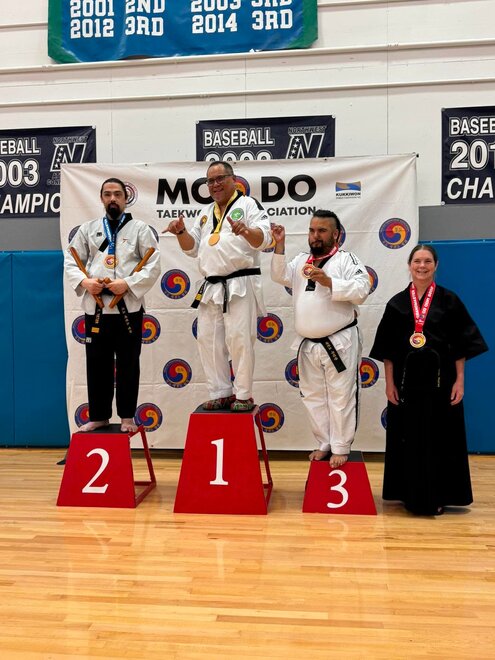 A martial artist intensely performing a move while other students watch in the background.