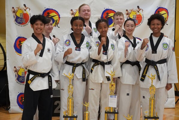 A group of Evergreen Taekwondo Academy students celebrating trophies won at a state tournament.