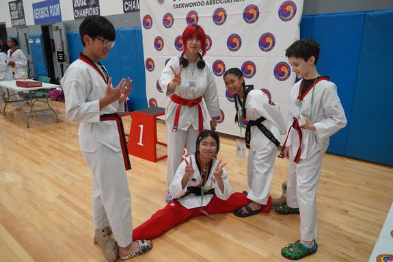 Two lines of students partnered together with one line using foam pads to help the other line practice blocking above their heads.