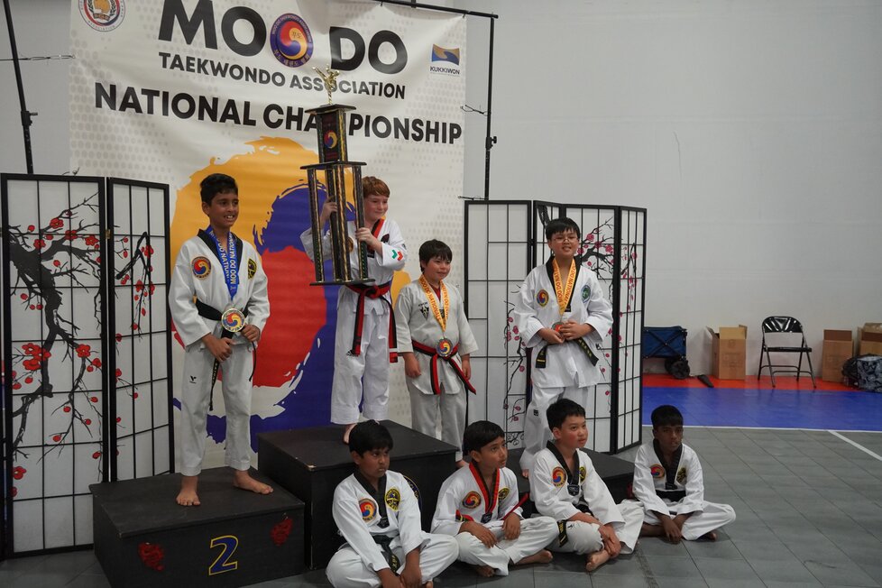 A group of people in martial arts uniforms celebrating as a group with their fists held high.