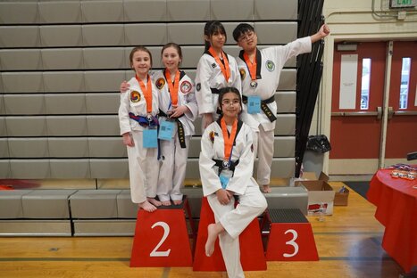 A martial artist intensely performing a move while other students watch in the background.