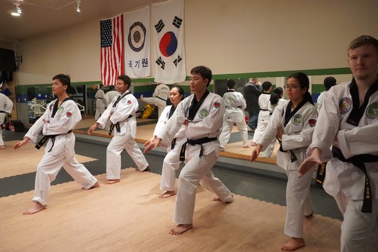 Black belt students performing a poomsae pattern together in sync