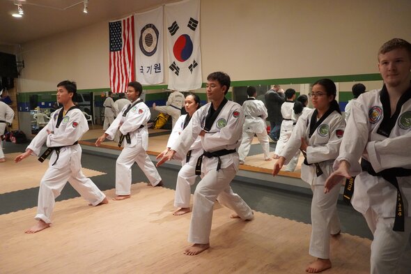 Black belt students performing a poomsae pattern together in sync