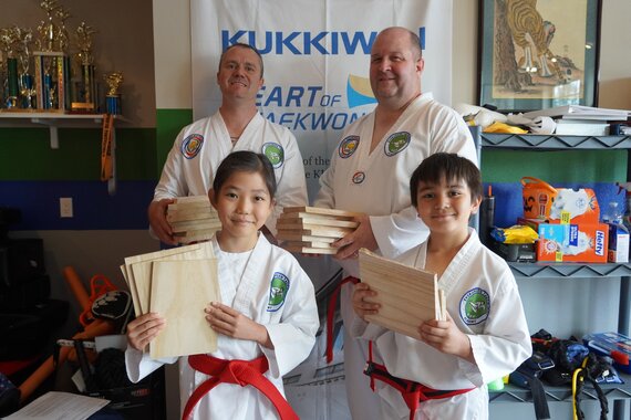 A group of martial art students showing their smiles and their broken boards after a belt test