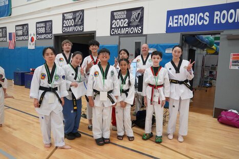A martial artist intensely performing a move while other students watch in the background.