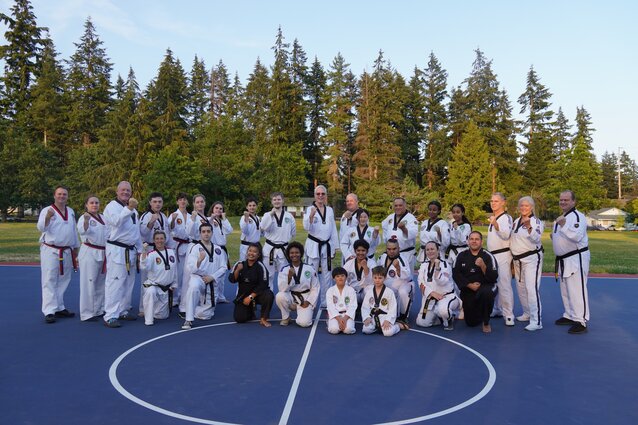 A group of people in martial arts uniforms celebrating as a group with their fists held high.