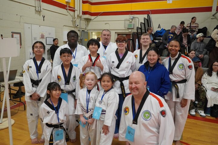 A group of cheerful kids and adults in martial arts uniforms