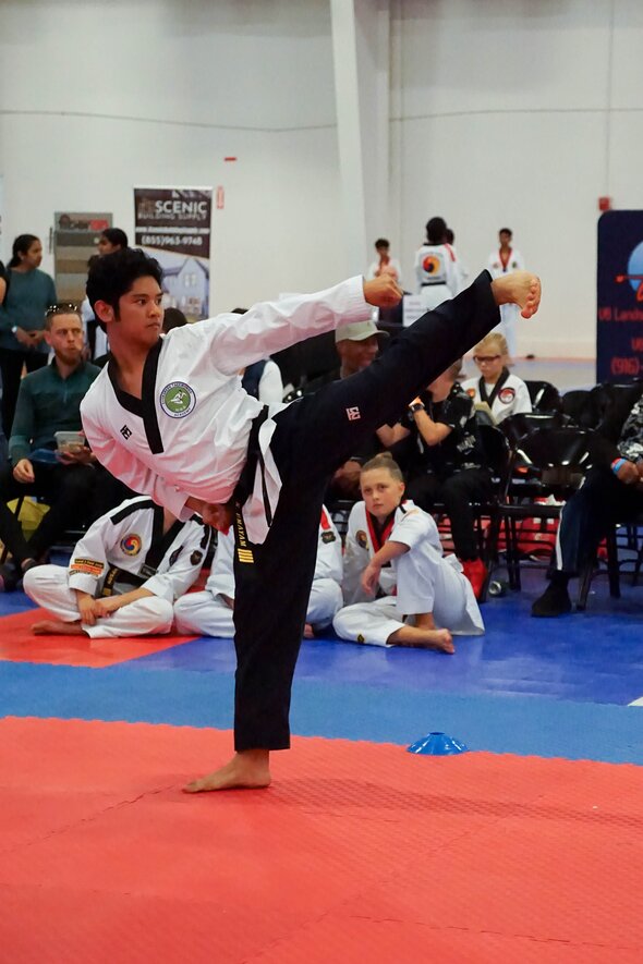 Poomsae athlete performing a sidekick at a tournament