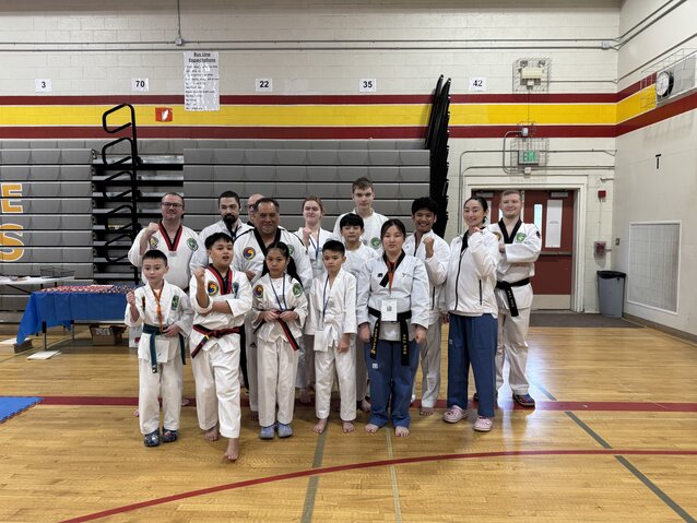 A group of people in martial arts uniforms celebrating as a group with their fists held high.