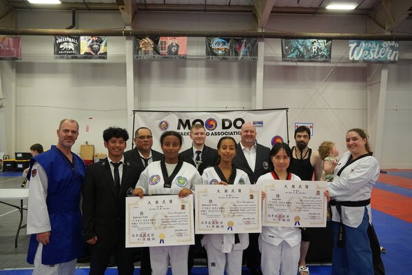 Group of new black belts celebrating their achievements at a promotion ceremony