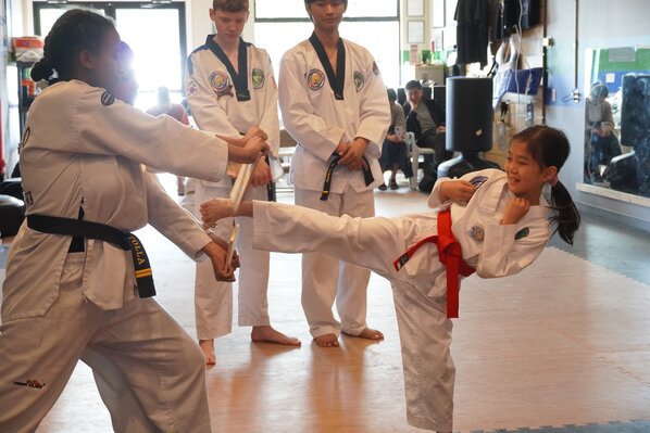 A student smiling as she breaks through boards using a kick