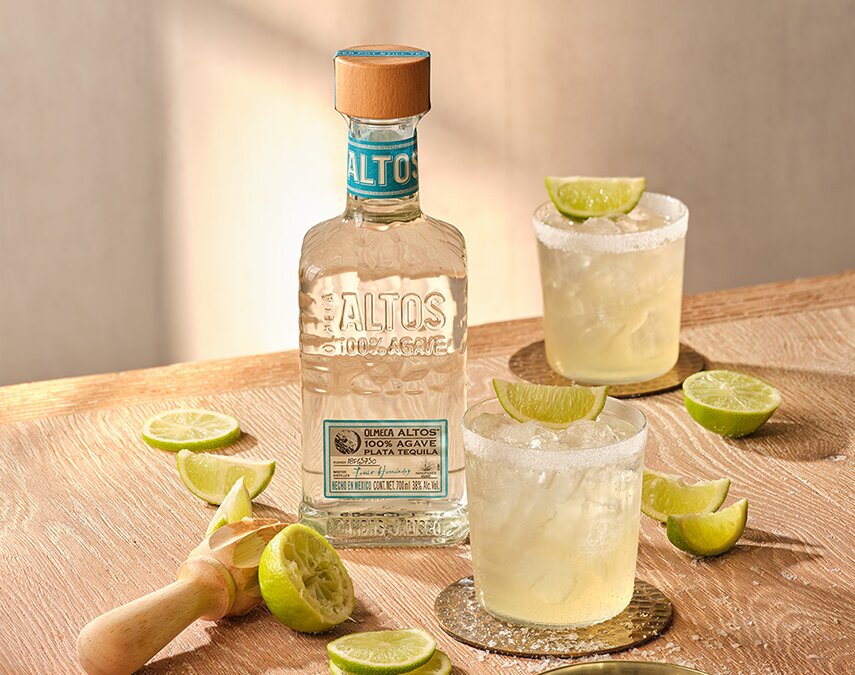 A bottle of Olmeca Altos Plata and two margarita cocktails.