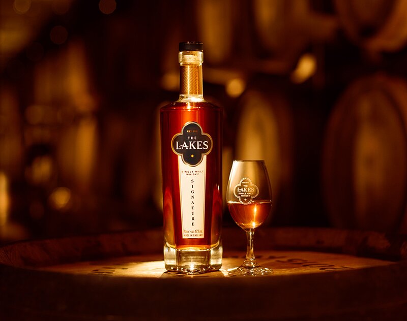 A bottle of The Lakes Signature Single Malt with a glass of whisky.
