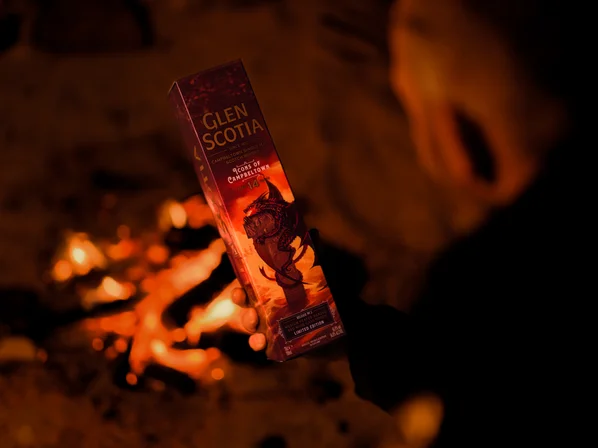 A presentation box for Glen Scotia 14yo Icons #2 being held in front of a bonfire.