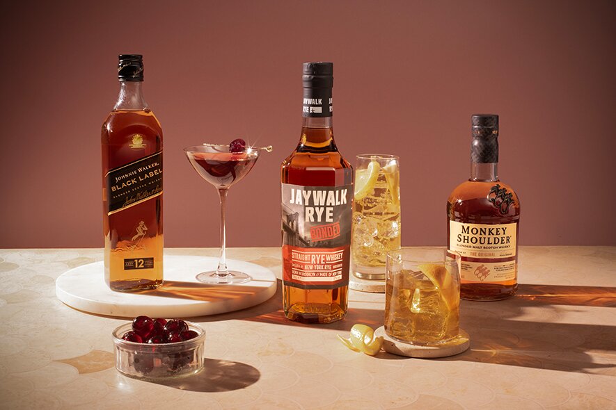 Bottles of Jaywalk, Johnnie Walker and Monkey Shoulder whisky alongside whisky cocktails.
