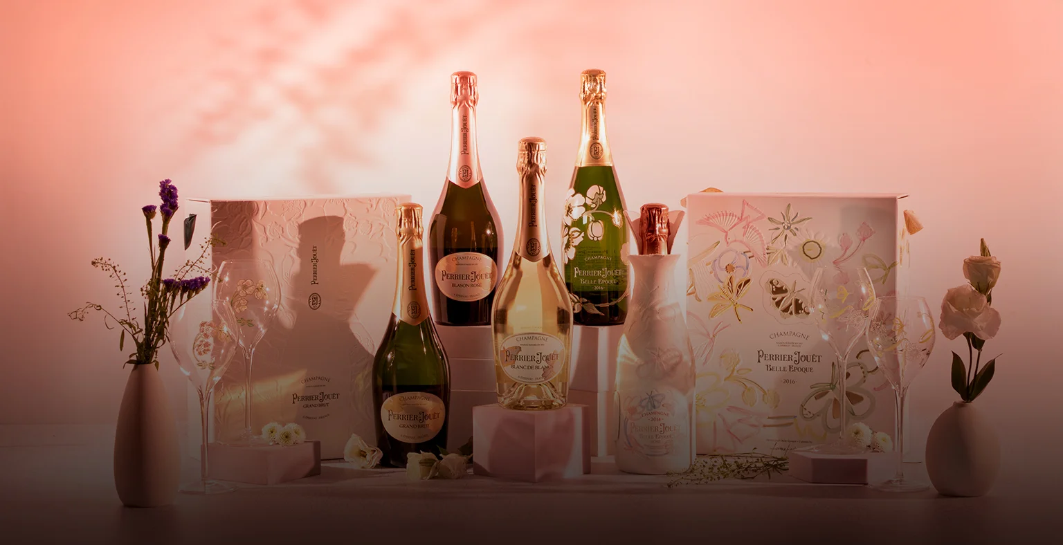 Five bottles of Perrier-Joet Champagne on a pink background.