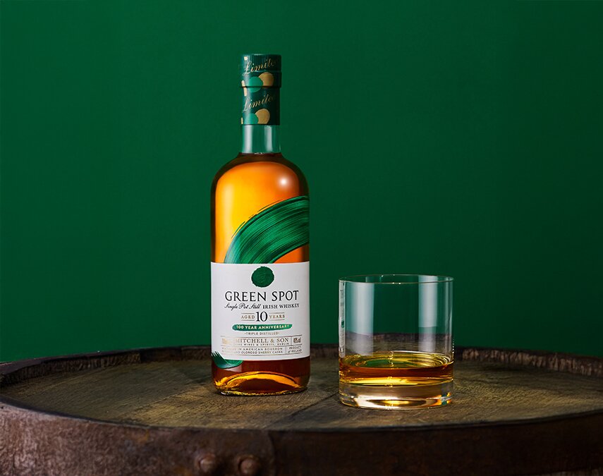 A bottle of Green Spot 10 Year Old 100 Year Anniversary bottle and a glass of whiskey.