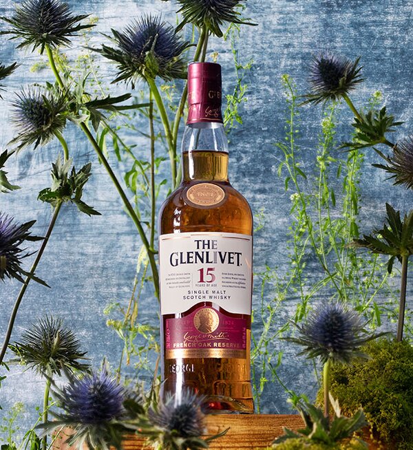 A bottle of The Glenlivet 15 Year Old French Oak Reserve surrounded by thistles. 