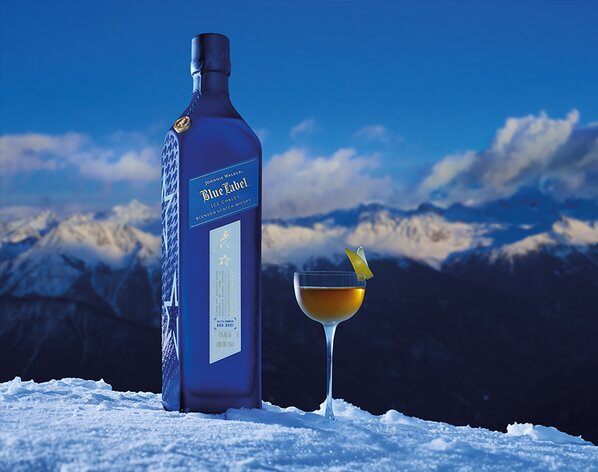 A bottle of Johnnie Walker Blue Label Ice Chalet next to a Ice Chalet Perfect Manhattan cocktail.