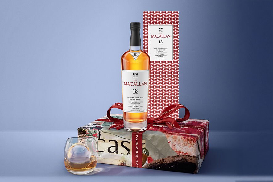 A bottle of Macallan 18yo on a present nest to a glass of whisky.