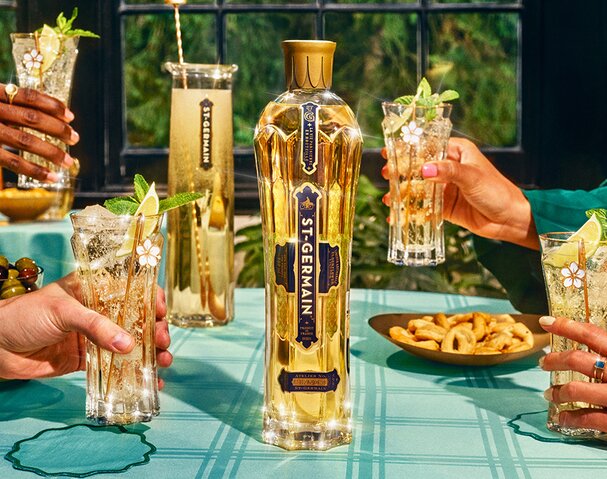 A bottle of St-Germain Elderflower Liqueur with four Hugo Spritz cocktails around it.