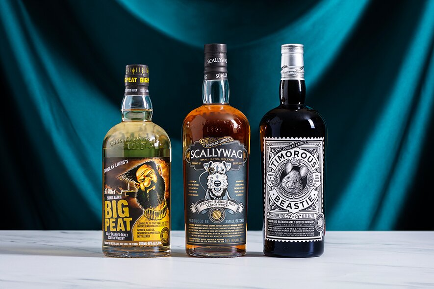 Three bottles of whisky from Douglas Laing against a blue backdrop.