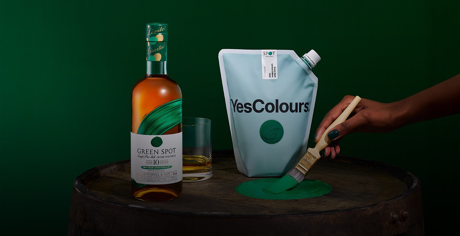 A bottle of Green Spot 10 Year Old 100 Year Anniversary bottle and a glass of whiskey.