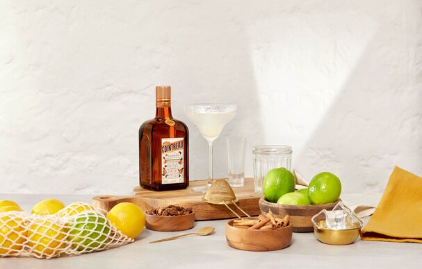 A bottle of Cointreau and a margarita with ingredients