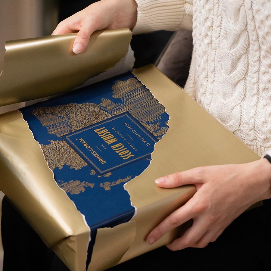 A Scotch Whisky advent calendar in wrapping paper being opened