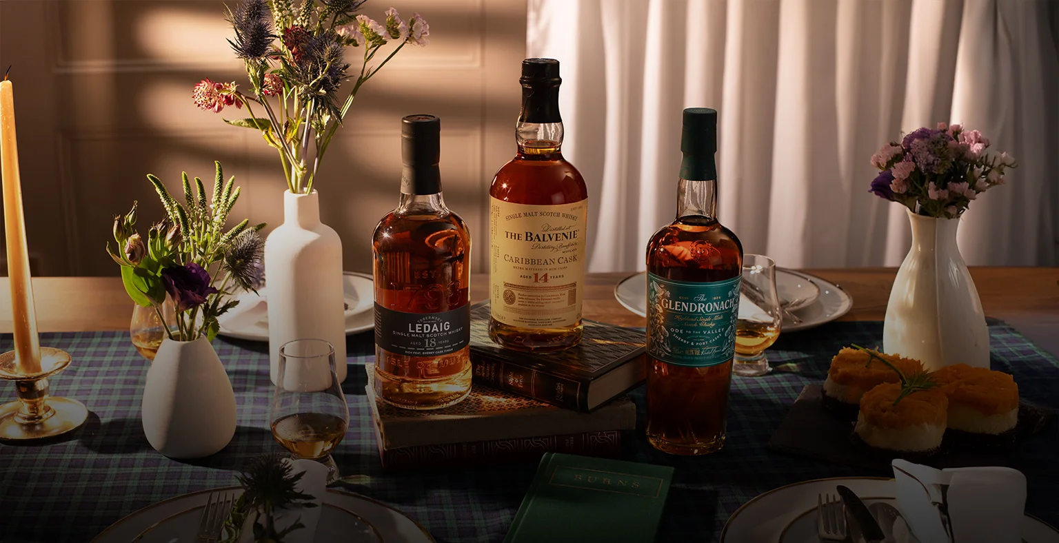 Three bottles of Scotch whisky on a table with blue tartan tablecloth.