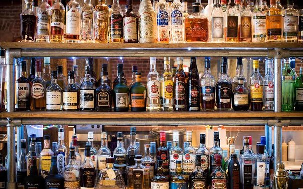 Different bottles of rums on a shelf, in a bar.