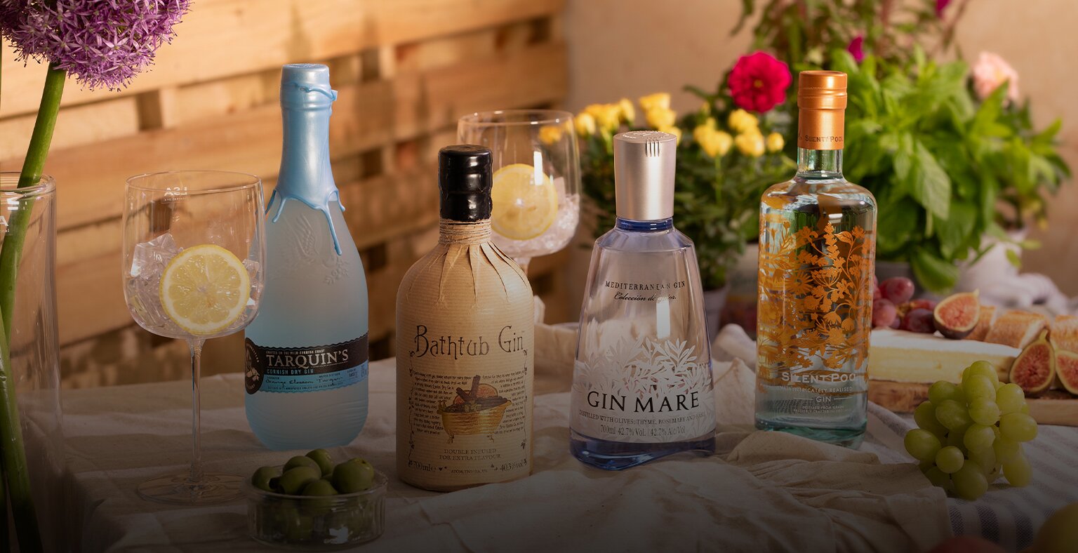 four bottles of gin on a table in a garden.