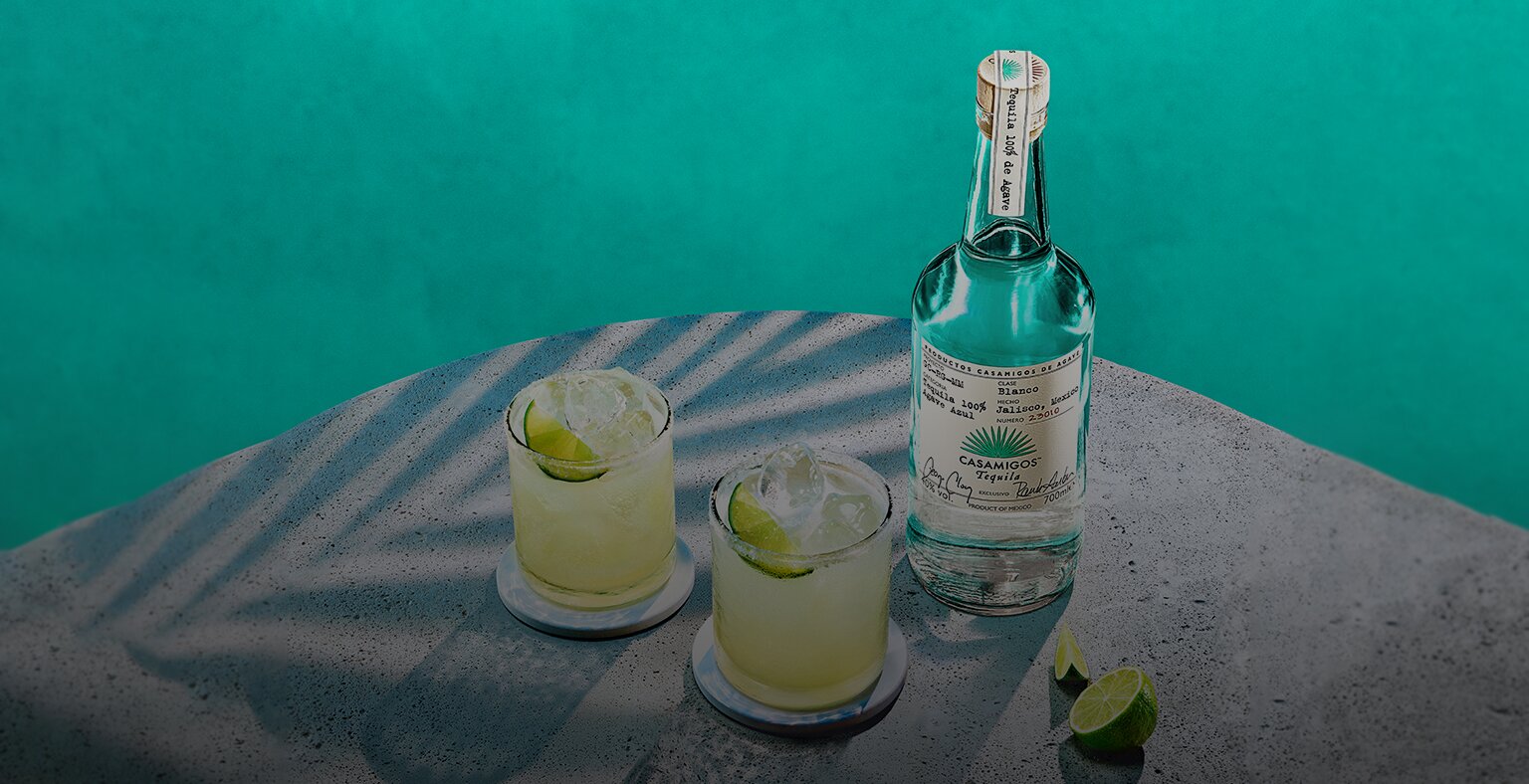 Bottle of Casamigos Blanco Tequila with two Margarita cocktails.