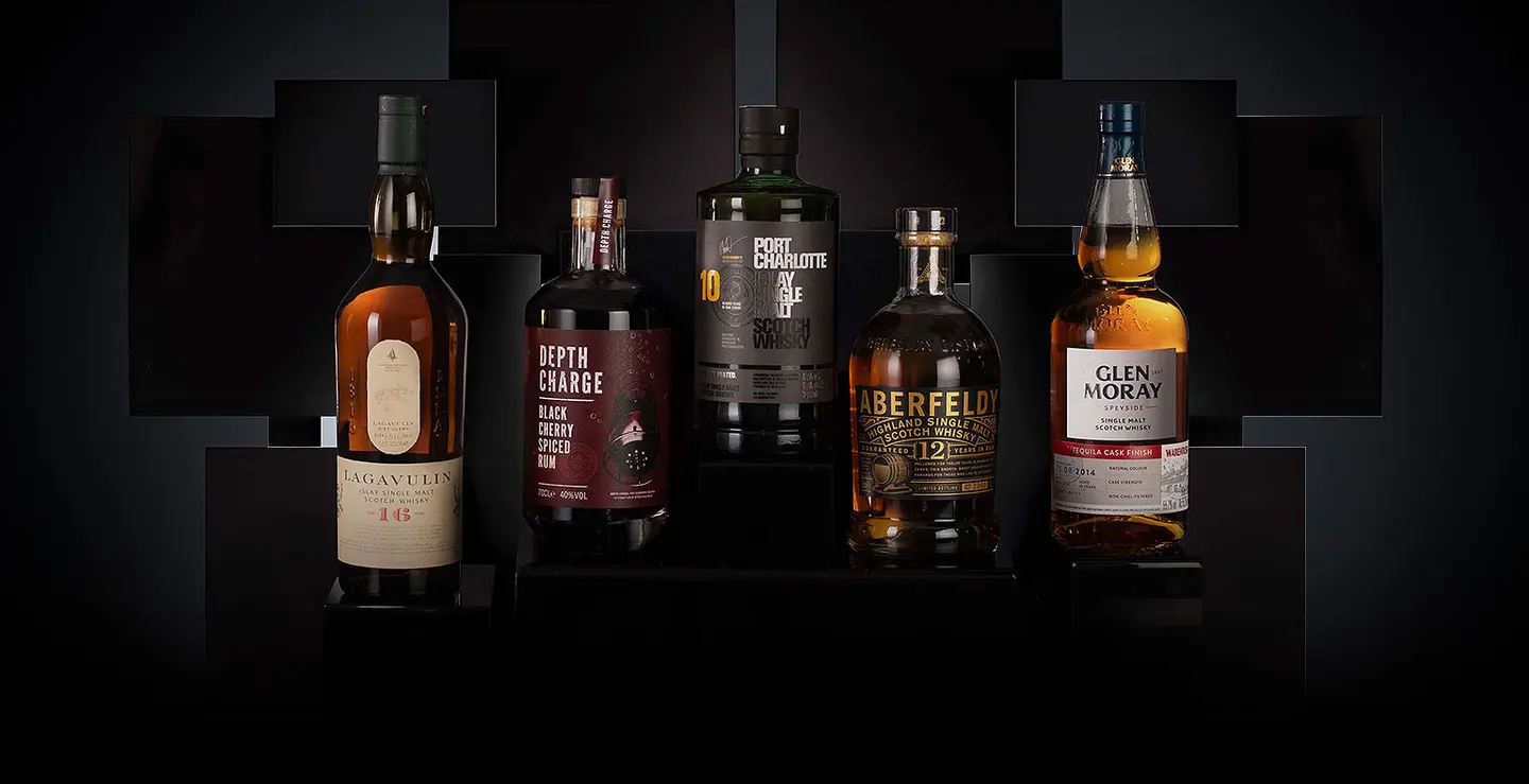 Five bottles of whisky and rum on a black background.