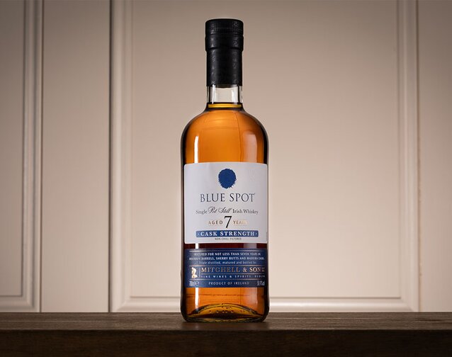 A bottle Spot Whiskey Blue Spot 7 Year Old against a cream paneling. 