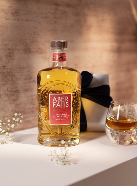 A bottle of Aber Falls single malt whisky against a pink and beige background. 