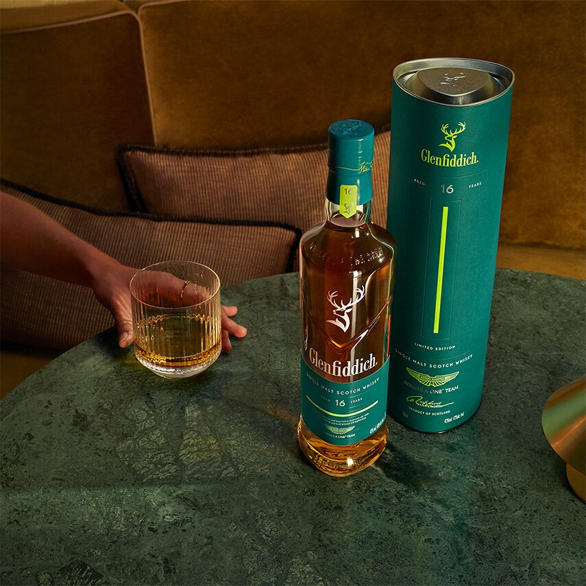 A bottle of Glenfiddich 16 Year Old x Aston Martin F1 next to a glass of whisky.