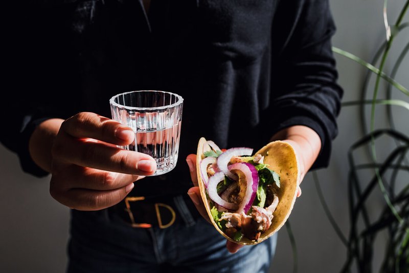 A glass of mezcal next to a taco