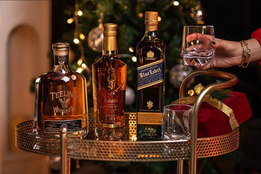 Three bottles of luxury whisky in a Christmas setting
