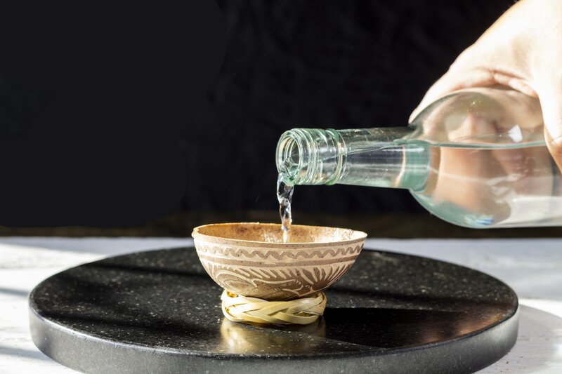 Mezcal being poured into a clay copita