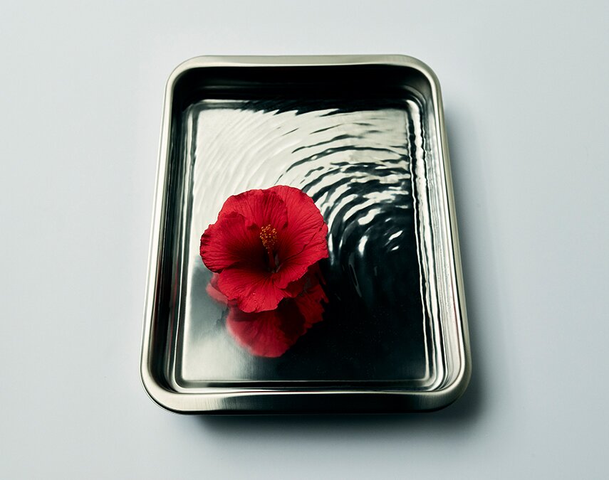 A metal tray with a red flower in it