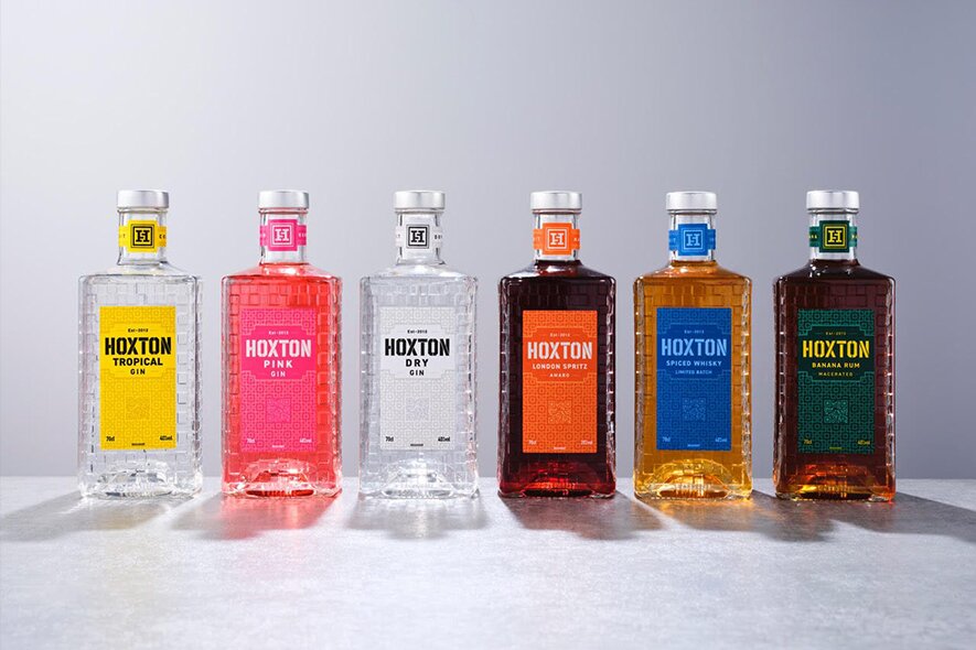 Six bottles of Hoxton rum, gin and whisky against a grey background.