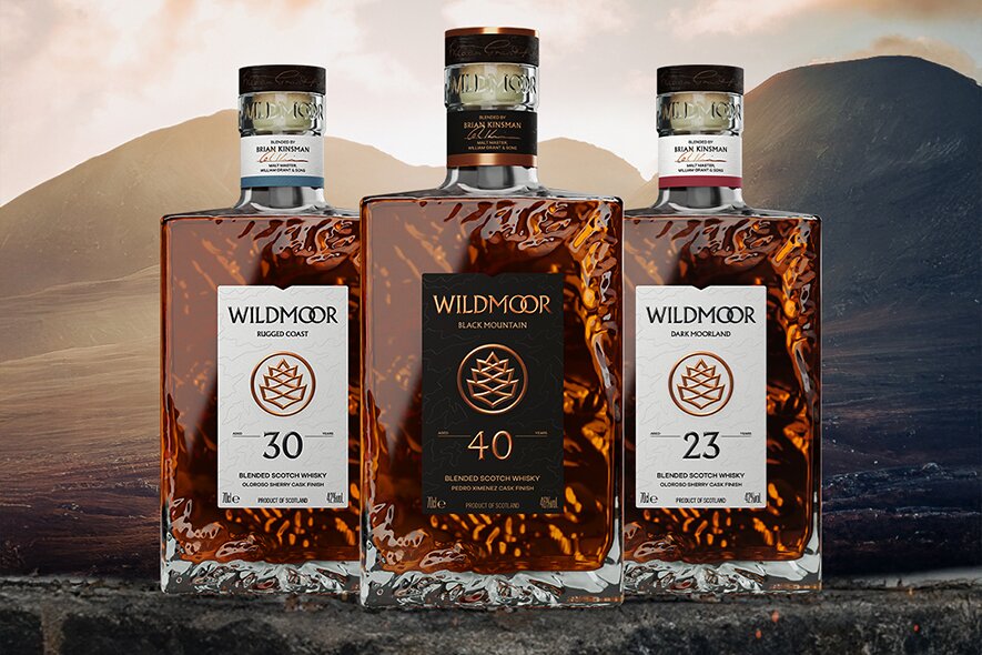 Three bottles of Wildmoor whisky against a mountain landscape.